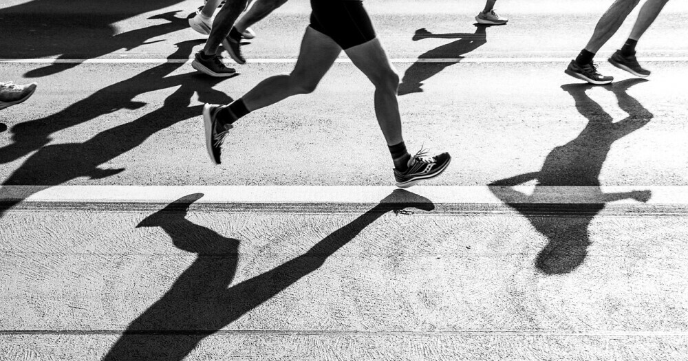 people running in a marathon in black and white with shadows